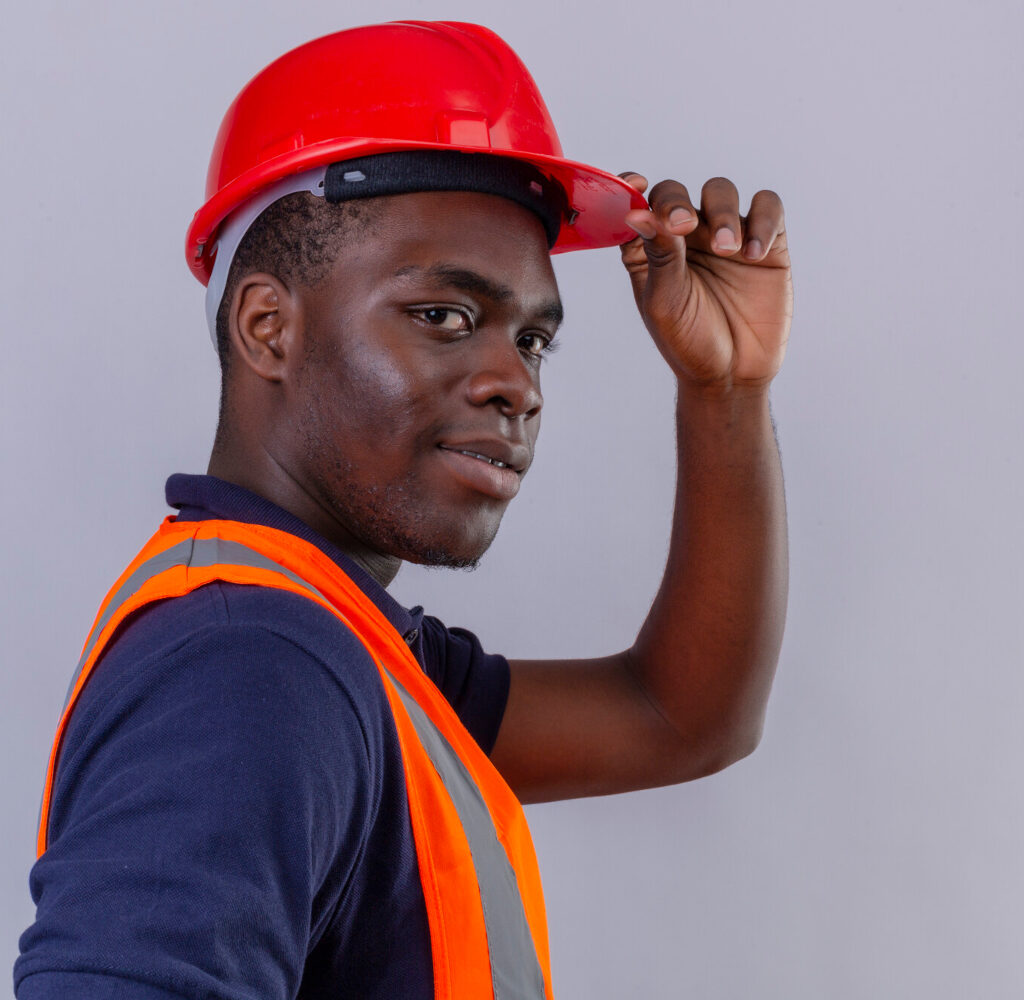 young-african-american-builder-man-wearing-construction-vest-safety-helmet-with-confident-smile-touching-helmet